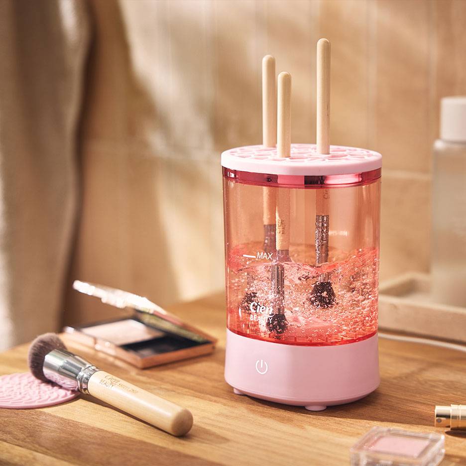 Růžový čistič make-up štětců se štětci v bublinkové vodě.