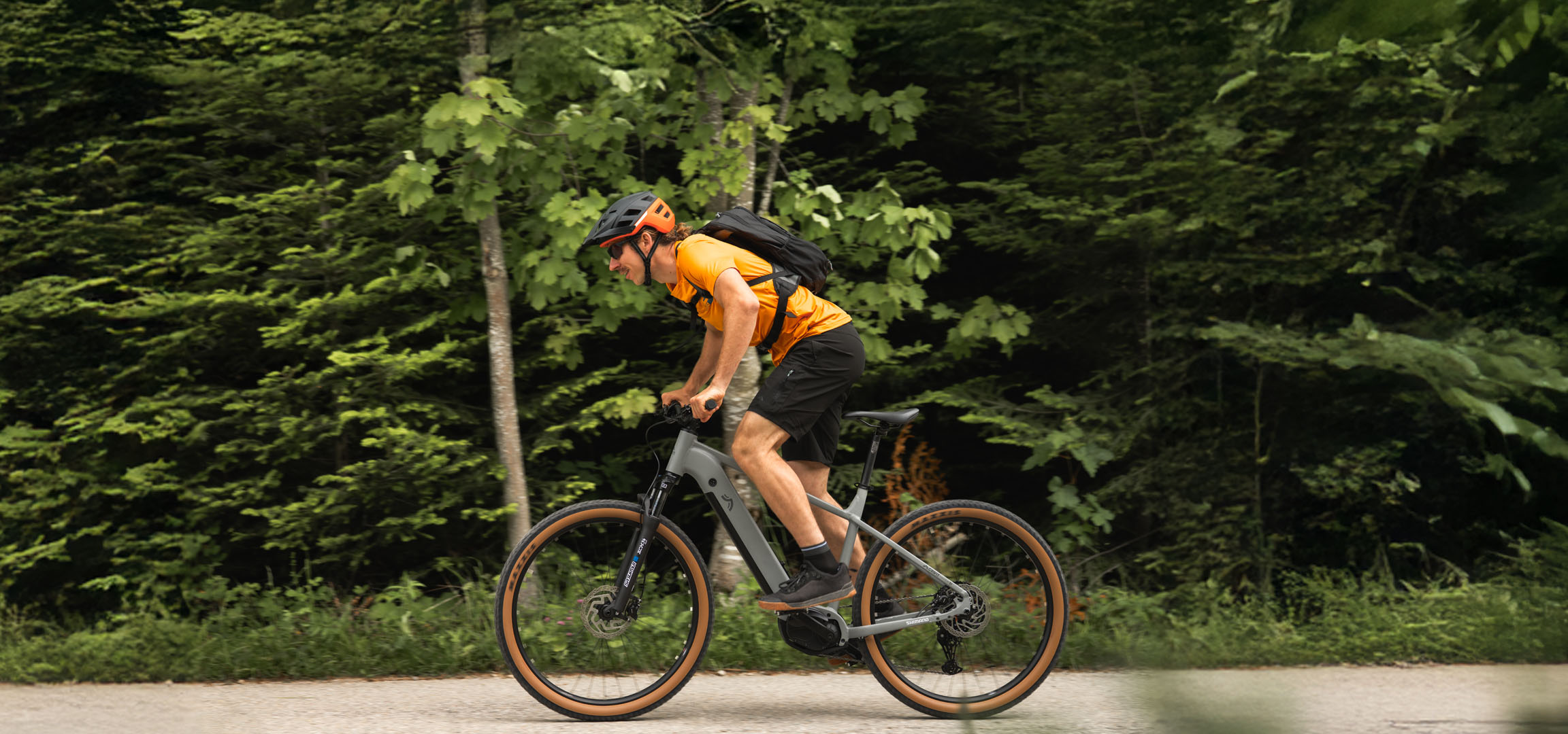 Muž jede na elektrokole Cube lesní cestou.