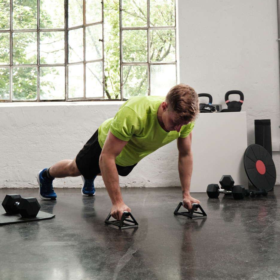 Muž dělá kliky s madly v posilovně.