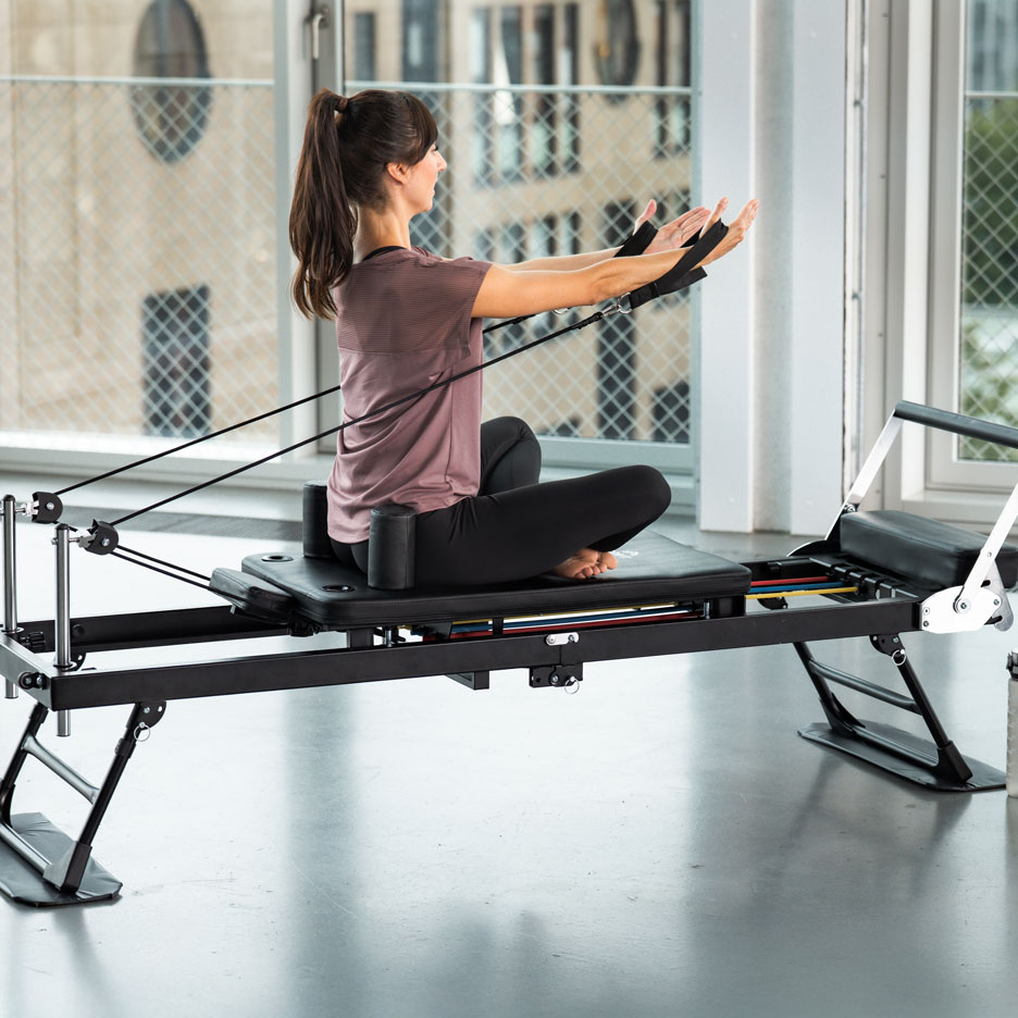 Žena cvičící na pilates stroji s odporovými pásy.