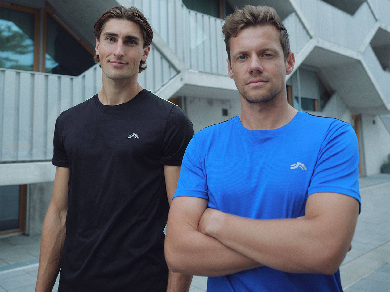 Dva muži v černých a modrých sportovních tričkách s logem.