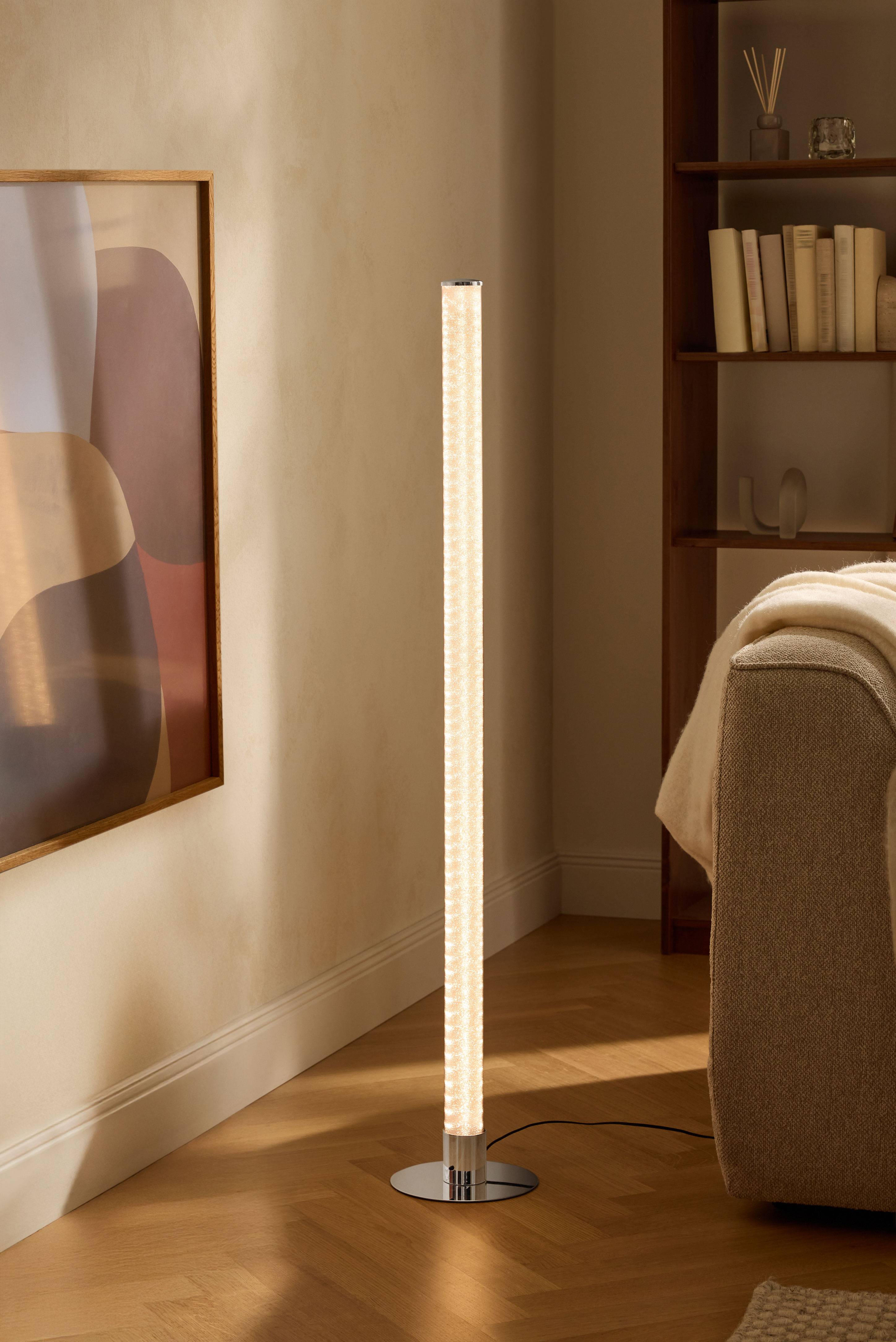 Moderní stojací lampa v obývacím pokoji s knihovnou a pohovkou.