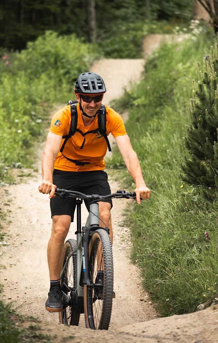 Muž se usmívá, když jede na horském kole po stezce.