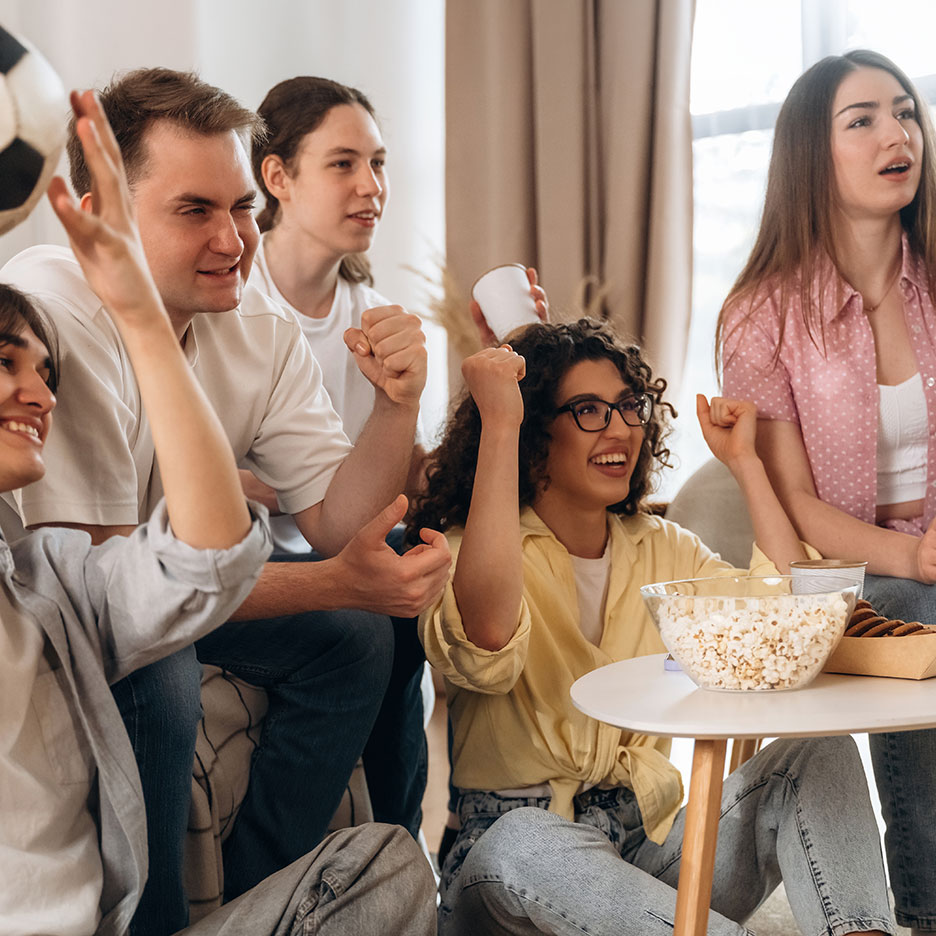 Přátelé fandí s popcornem a občerstvením při sledování sportu.