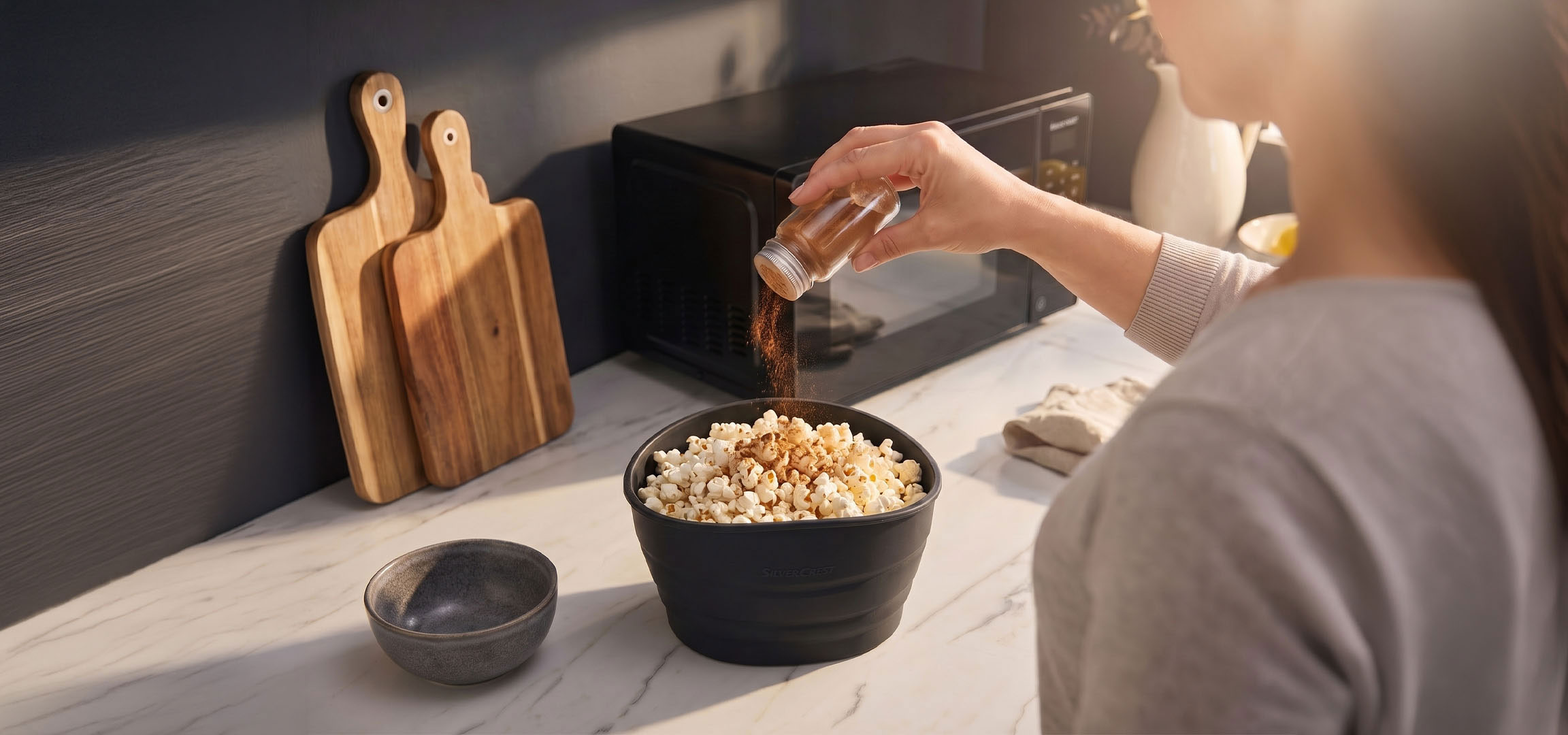 Obrázek vytvořený AI: Popcorn v černé misce kořeněný kořením, vedle dřevěných prkének.