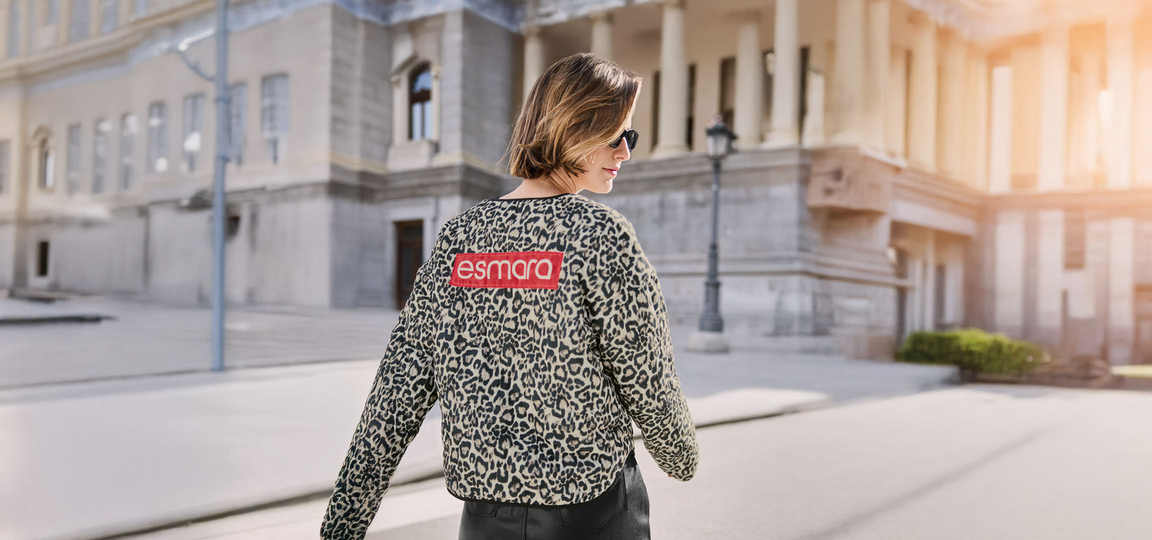 Žena v Esmara leopardí bundě, slunečních brýlích, na městské ulici.