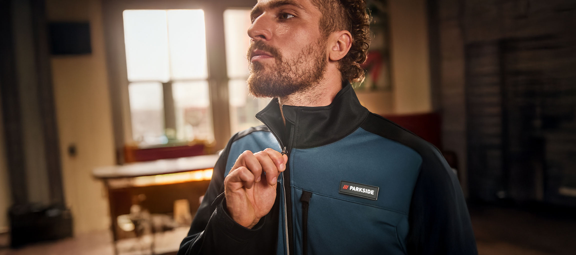 Muž v modro-černé pracovní bundě Parkside si ji zapíná