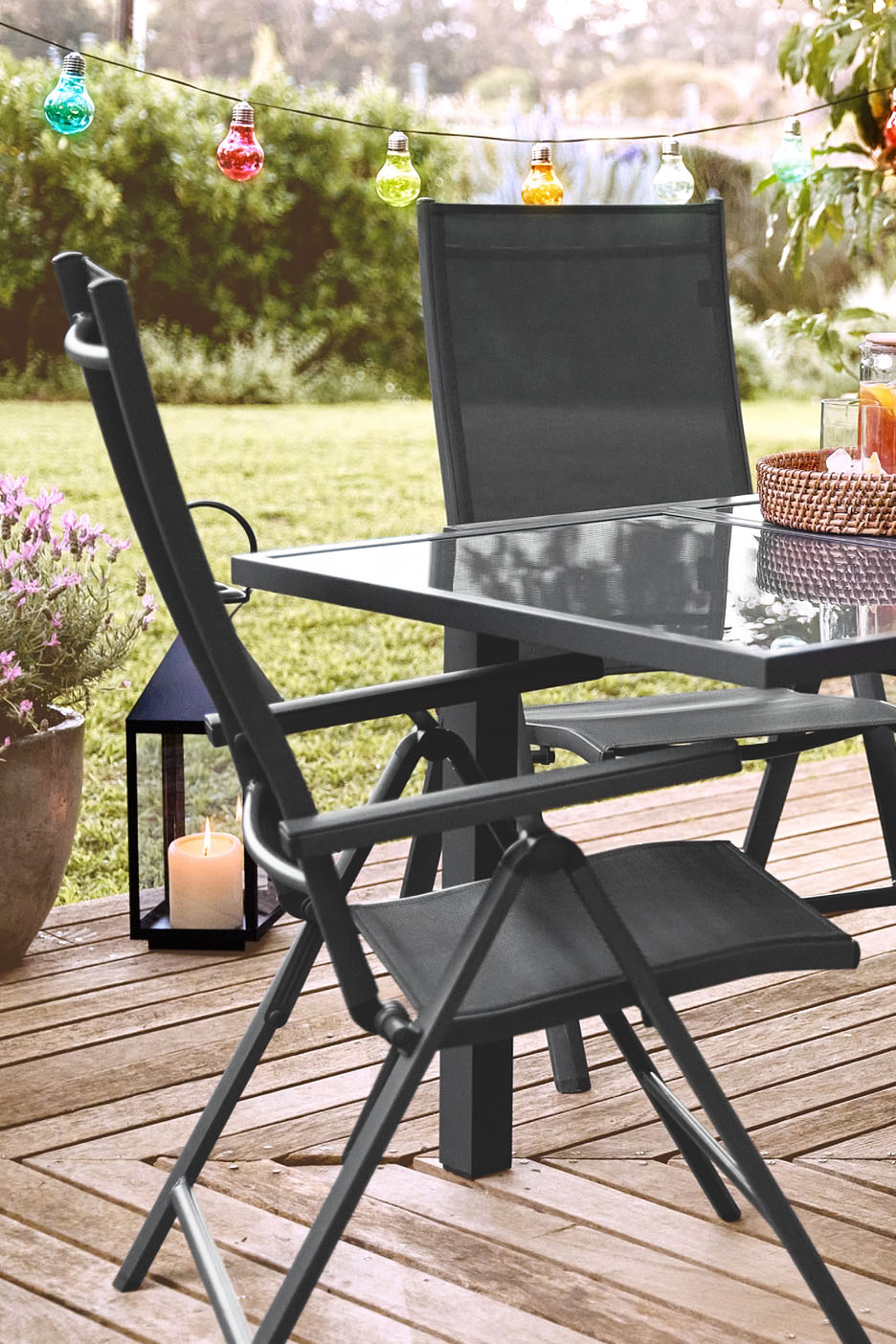 Conjunto de móveis de jardim de metal preto com cadeiras dobráveis e mesa de vidro.
