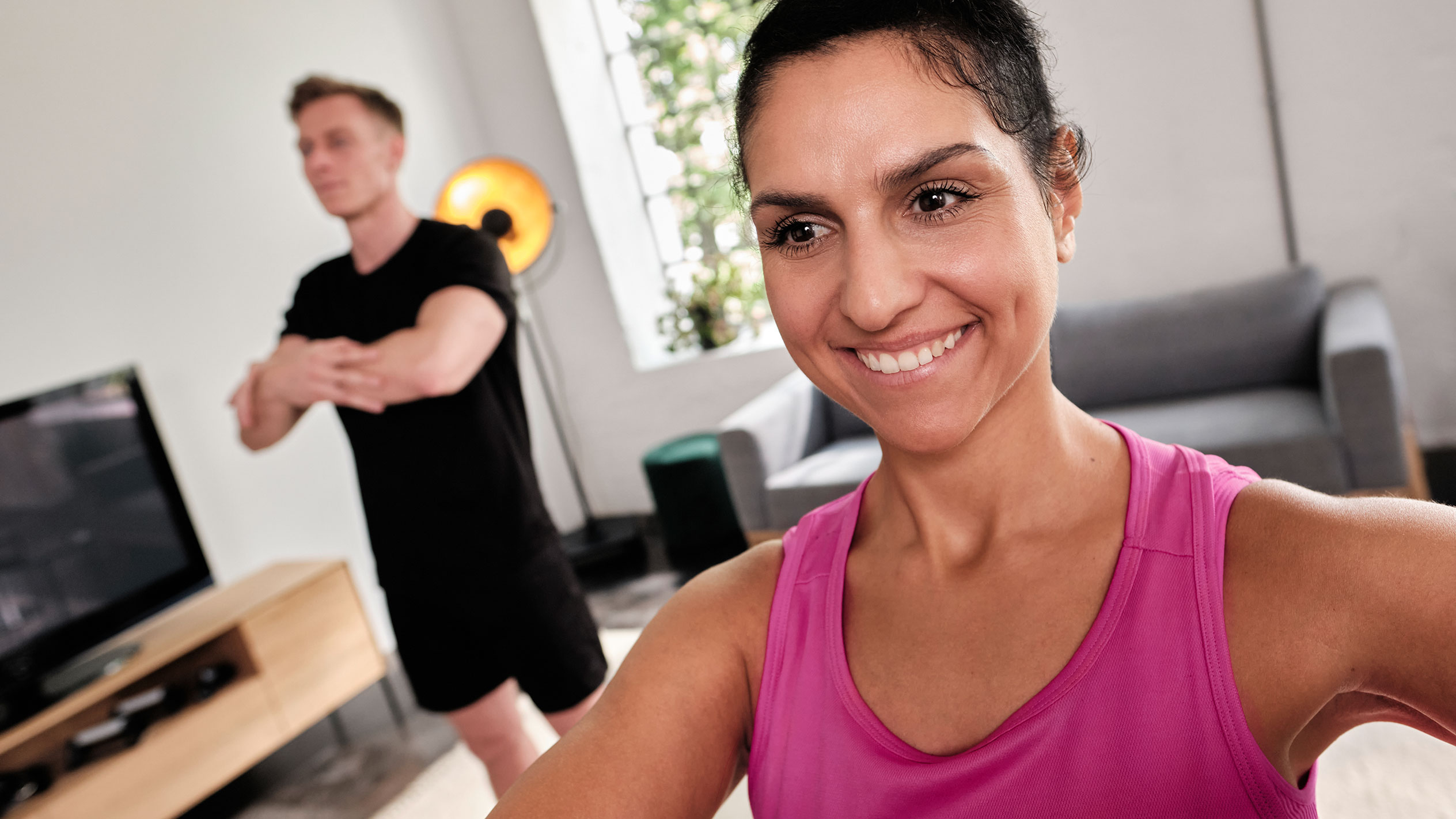 Usměvavá žena cvičí doma se svým partnerem.