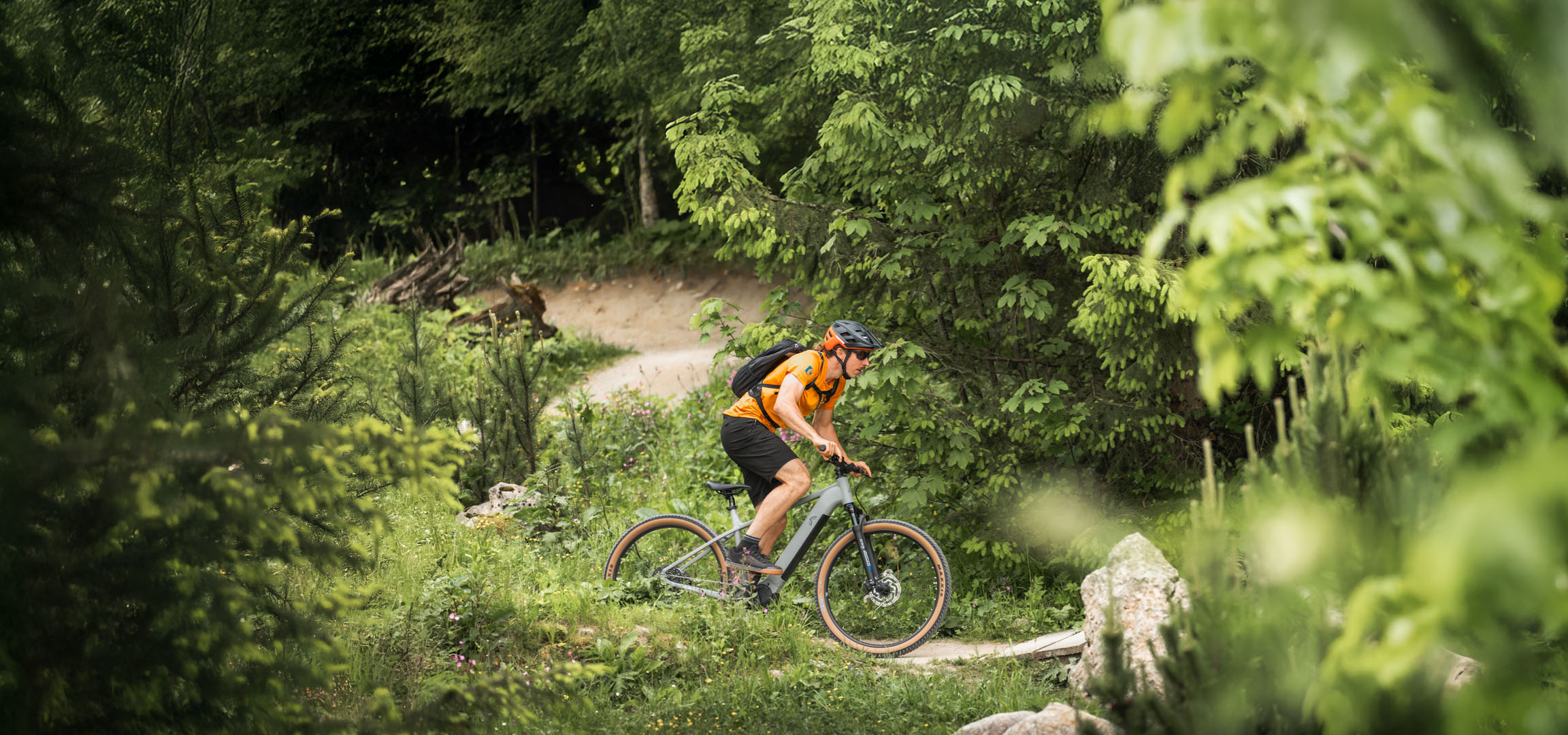Cyklista si užívá jízdu na elektrokole po lesní cestě.