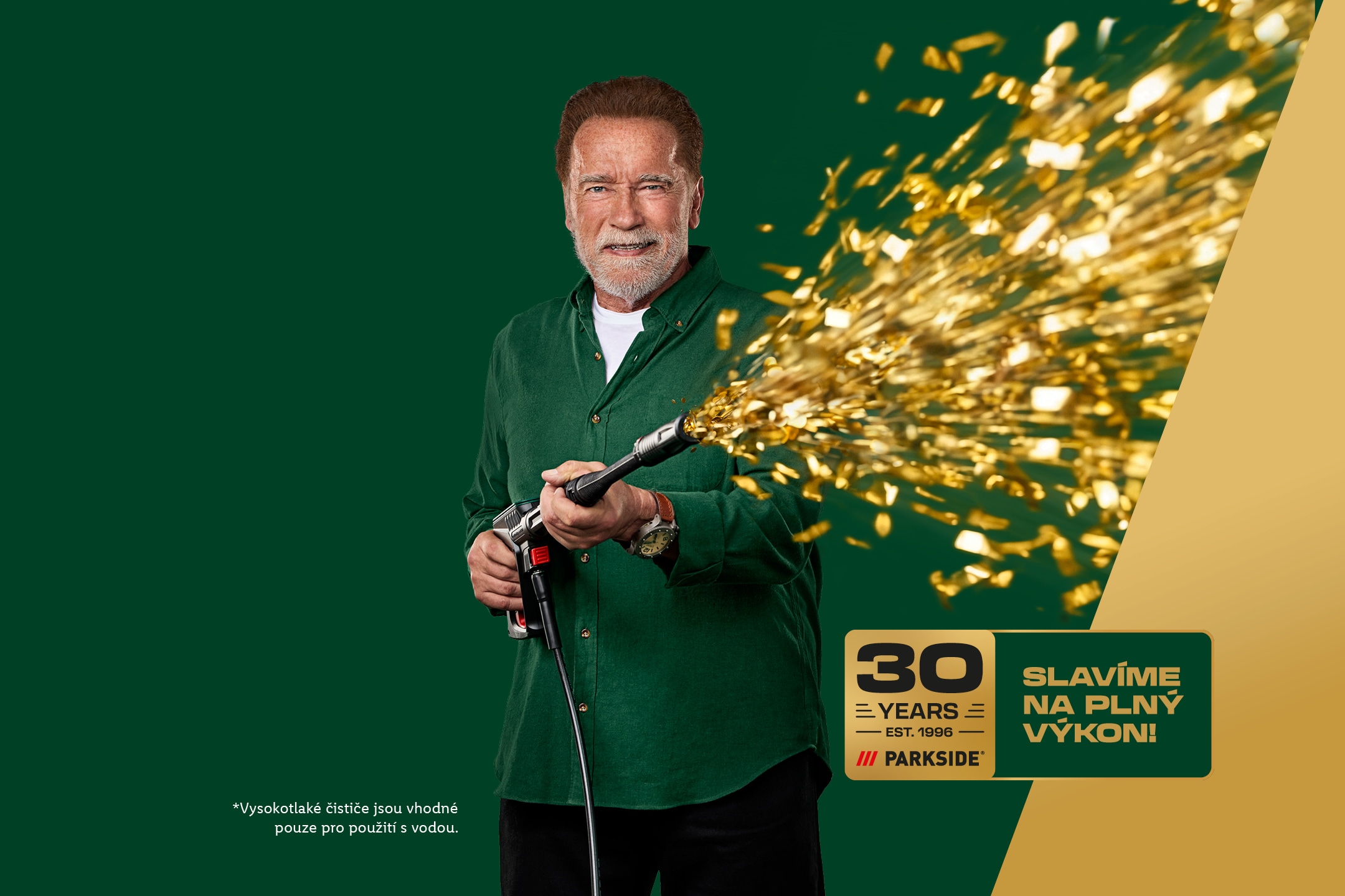 Arnold Schwarzenegger s tlakovou myčkou stříkající konfety, oslavující 30 let.
