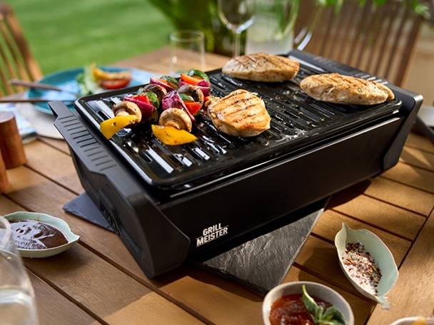 Gril na dřevěné uhlí s aktivní ventilací Grill Meister s kuřecím masem a zeleninou na grilu.