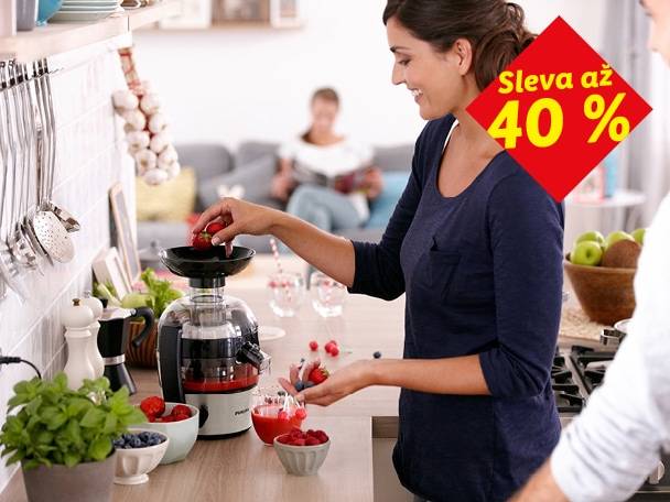 Žena připravuje čerstvou šťávu s odšťavňovačem, sleva až 40 %.