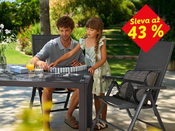 Muž a dívka hrají domino u zahradního stolu, sleva až 43 % na zahradní nábytek.
