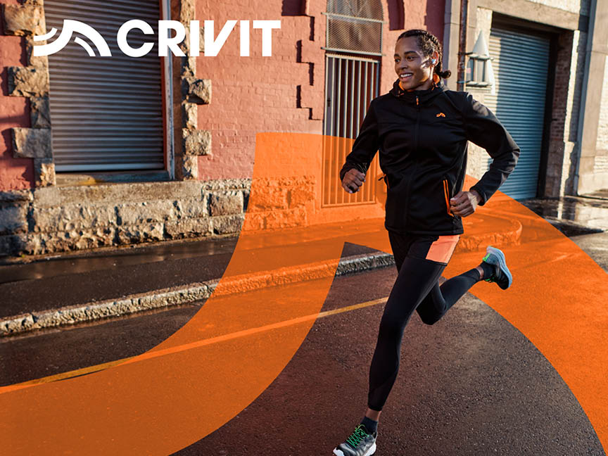 Žena v černém sportovním oblečení Crivit běží po ulici.