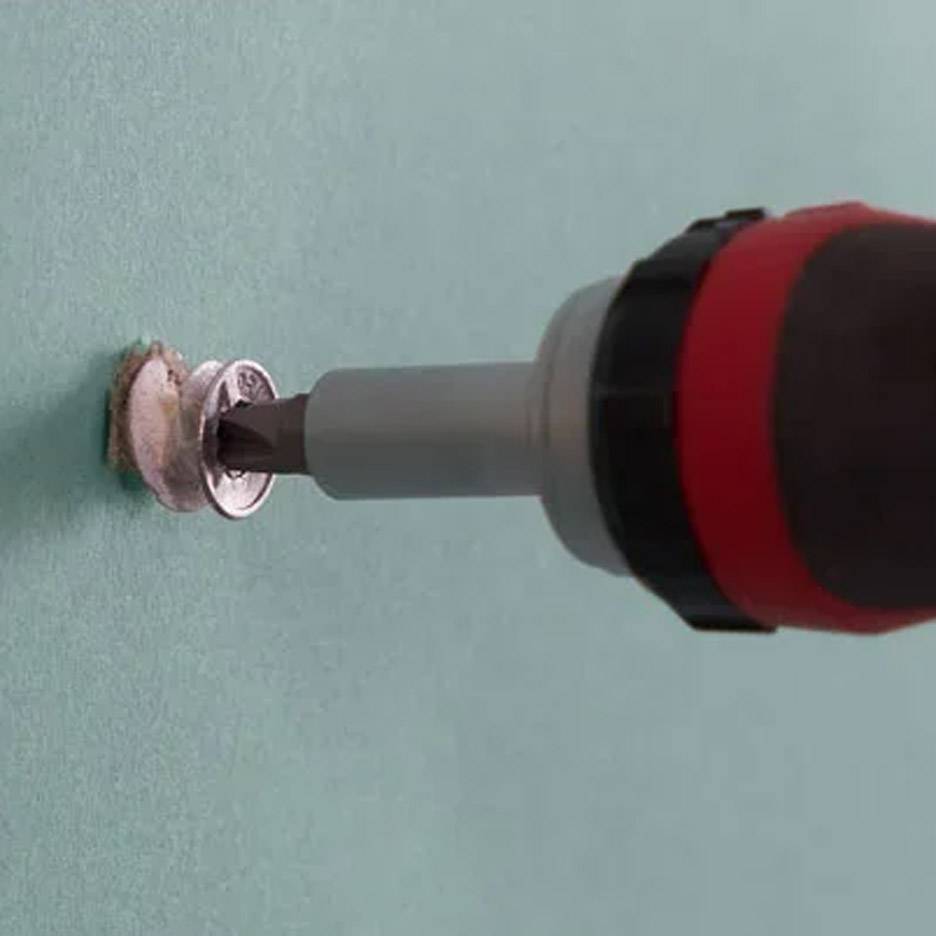 Elektrický šroubovák s vrtákem vkládající šroub do zdi.
