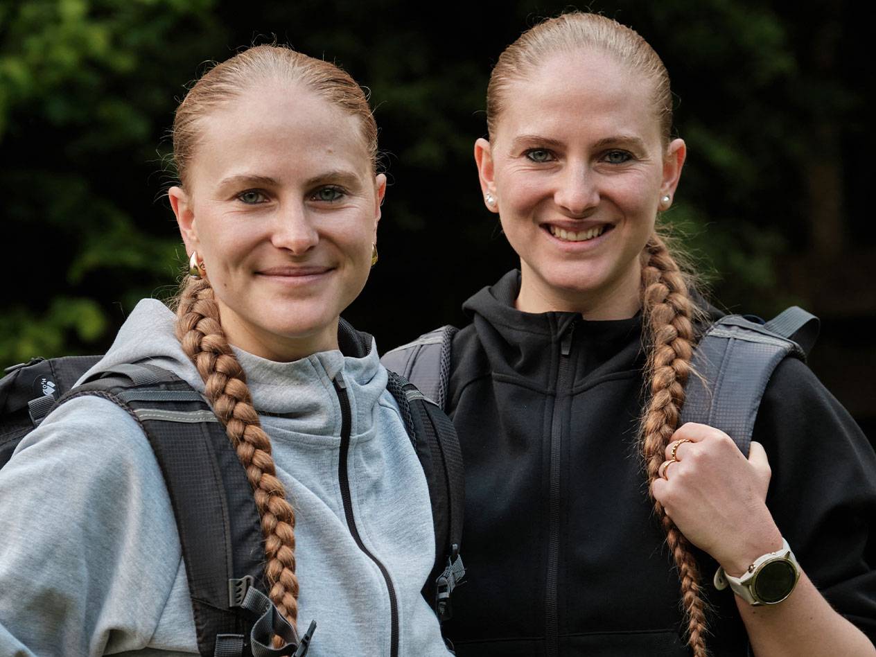 Dvě ženy s batohy stojí pohromadě.